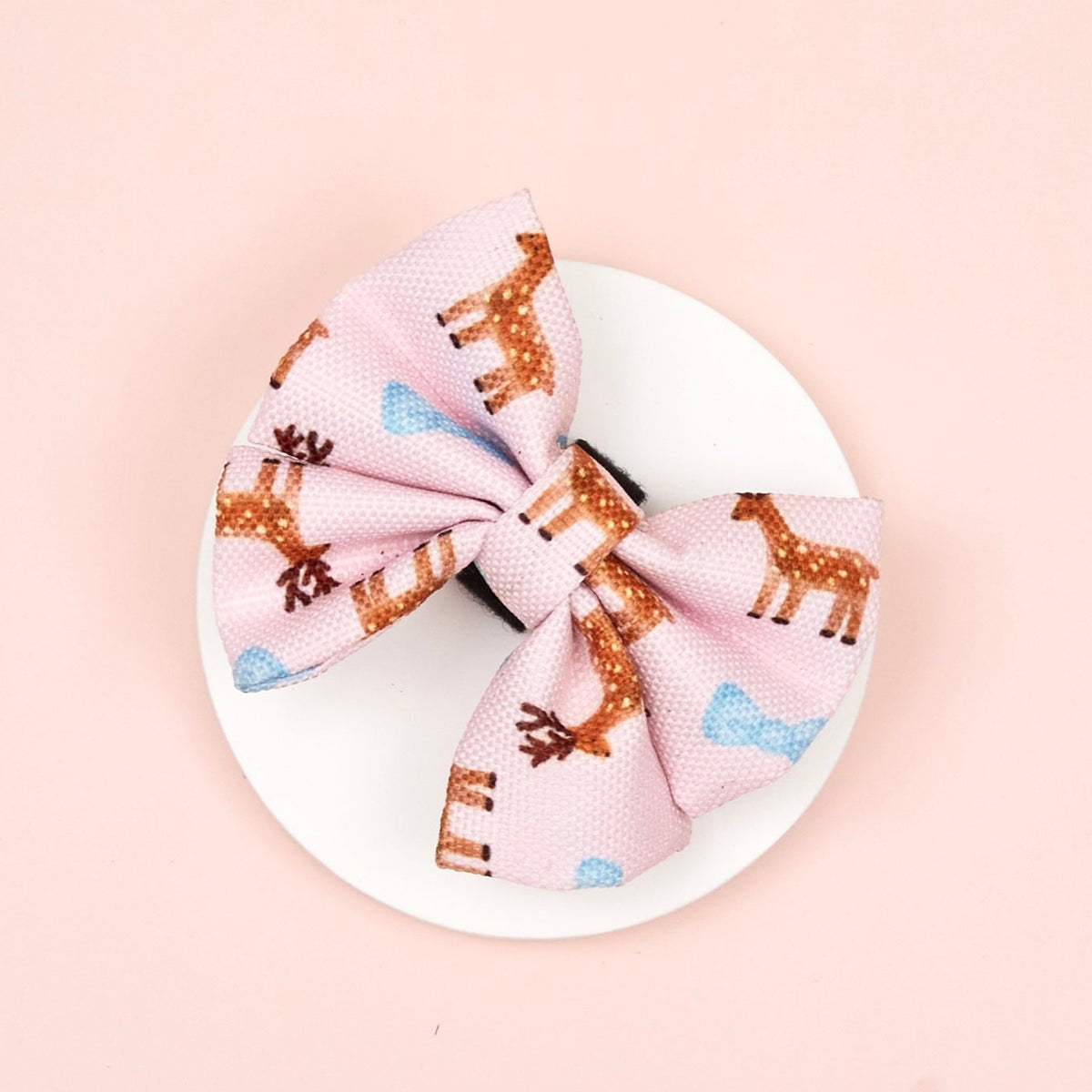 Decorative bow with deer pattern on a white plate against a pink background
