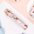 Pink floral dog collar with gold hardware on a white surface