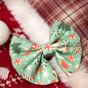 Christmas-themed bow on a red fabric background with candy cane and plaid patterns.