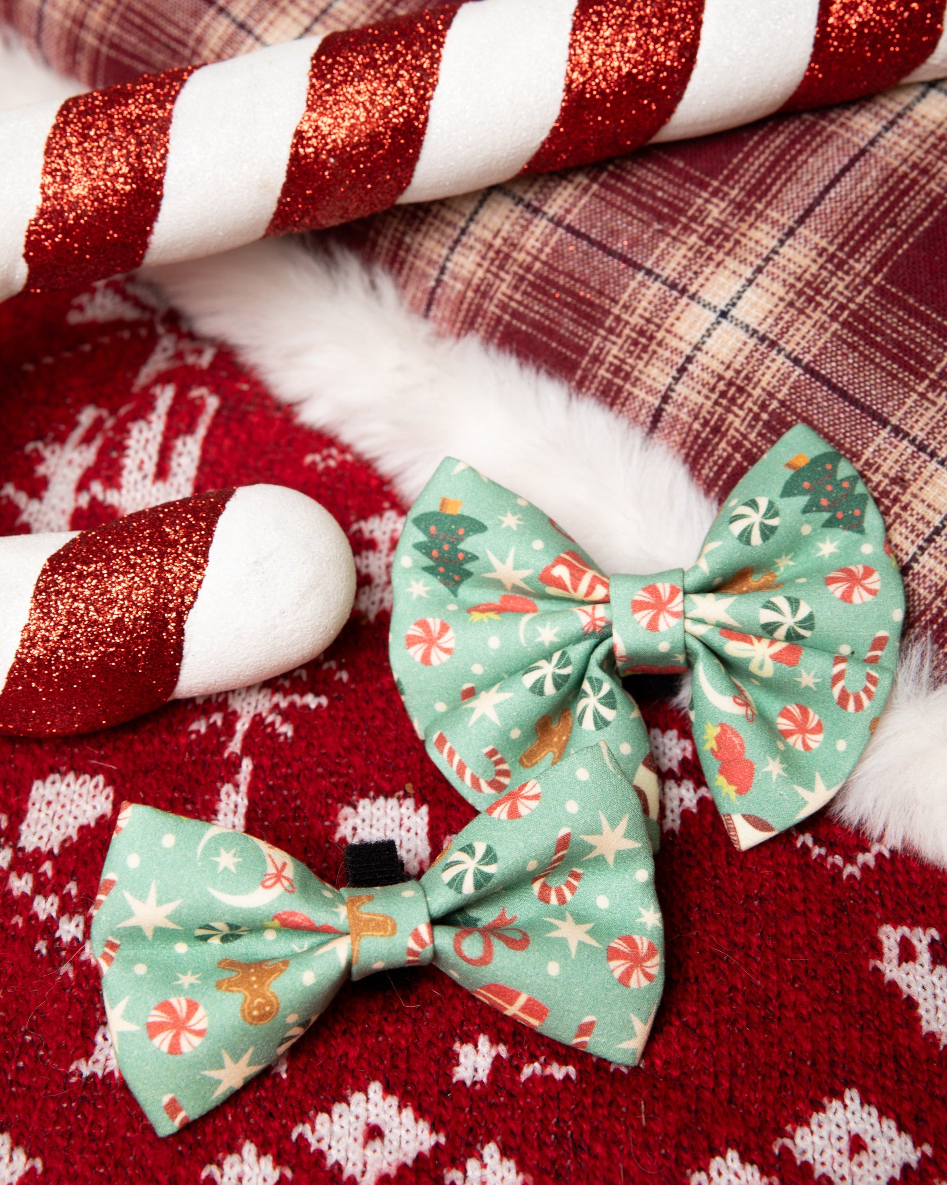 Two green floral-patterned bows on a red fabric background with candy canes.